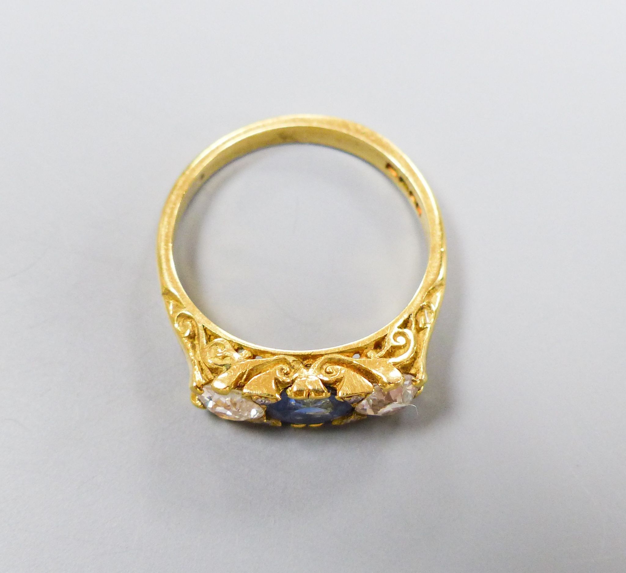 A 1970's Victorian style 18ct gold, single stone synthetic? sapphire and two stone diamond set ring, size N, gross weight 4.3 grams